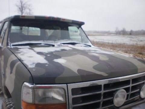 1995 Ford Bronco - This pickup truck features a camouflage paint job and is parked in a snowy, rural landscape.