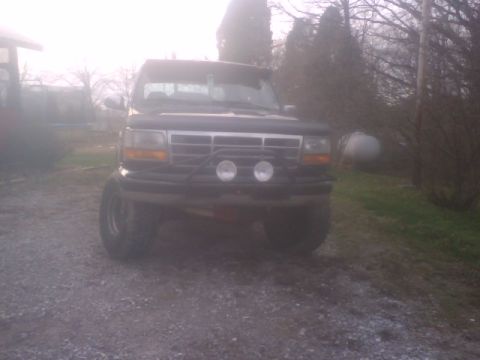 1995 Ford Bronco - A black Ford Bronco is parked on a gravel driveway with trees in the background.