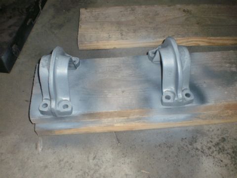 1995 Ford Bronco - Two gray metal brackets are shown resting on wooden planks, likely awaiting installation or painting.