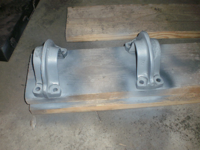 Two gray metal brackets on wooden planks