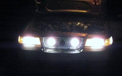 2000 Mercury Grand Marquis - The front of a 2000 Mercury Grand Marquis is shown at night with its headlights illuminated and the hood raised.