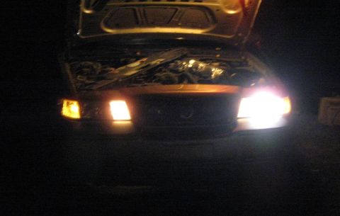 2000 Mercury Grand Marquis - Front view of a car at night with the hood open, revealing the engine and illuminated headlights.