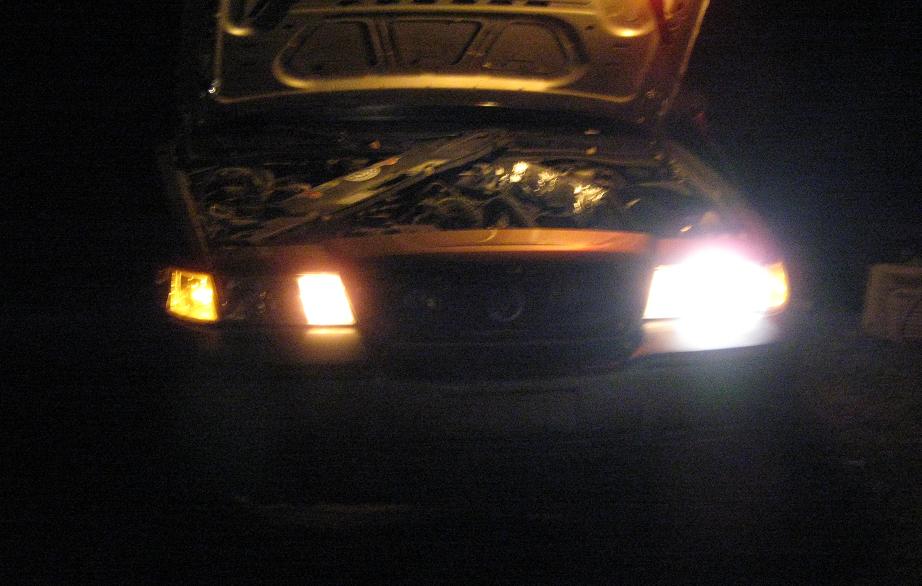 Car with hood open, showing engine and headlights at night