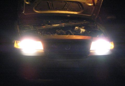 2000 Mercury Grand Marquis - The front of a 2000 Mercury Grand Marquis is shown with the hood open and headlights illuminated at night.