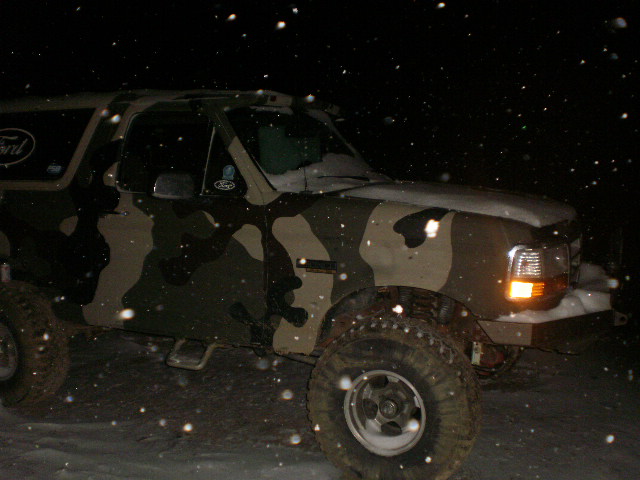 Camouflaged Ford Bronco in the snow at night