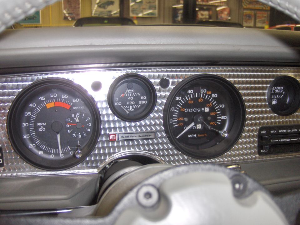 Car dashboard with tachometer, speedometer, oil pressure gauge, and fuel gauge. Diamond plate trim