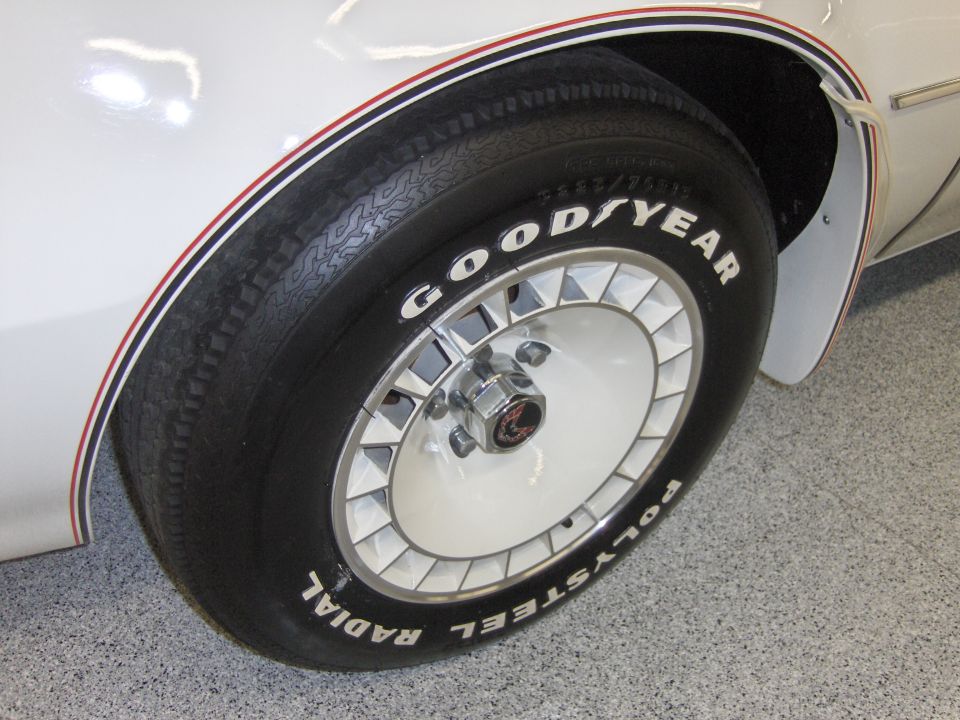 White car wheel with red and blue pinstripes on fender, Goodyear Radial Polysteel tires
