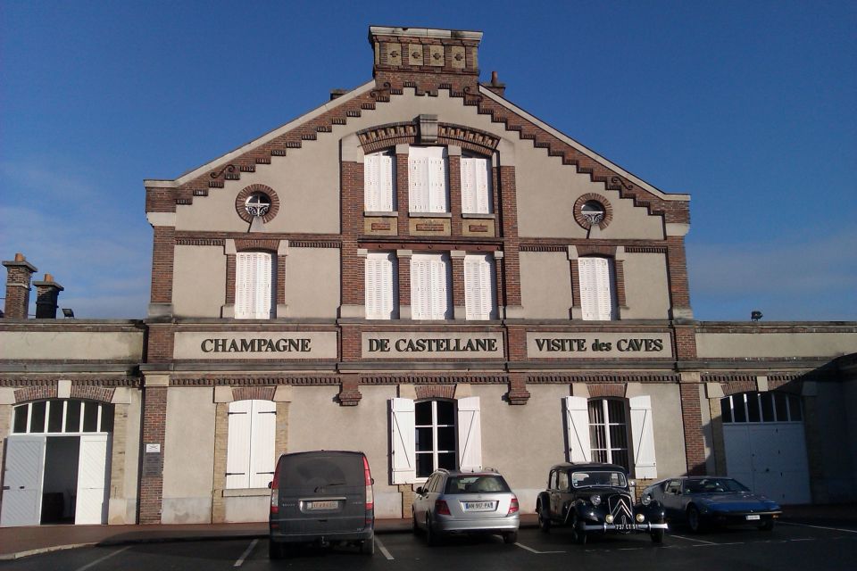Building with 'Champagne de Castellane Visite des Caves' text, parked cars in front