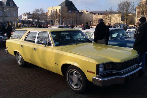 1991 Ford LTD Crown Victoria - A yellow station wagon is parked on a brick surface with other vehicles and buildings in the background.
