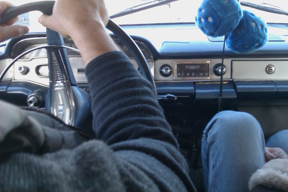 Interior view of a vintage car dashboard with fuzzy dice hanging from the rearview mirror