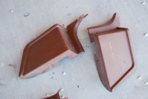 1982 Ford Bronco - Two brown plastic trim pieces are shown on a concrete surface.