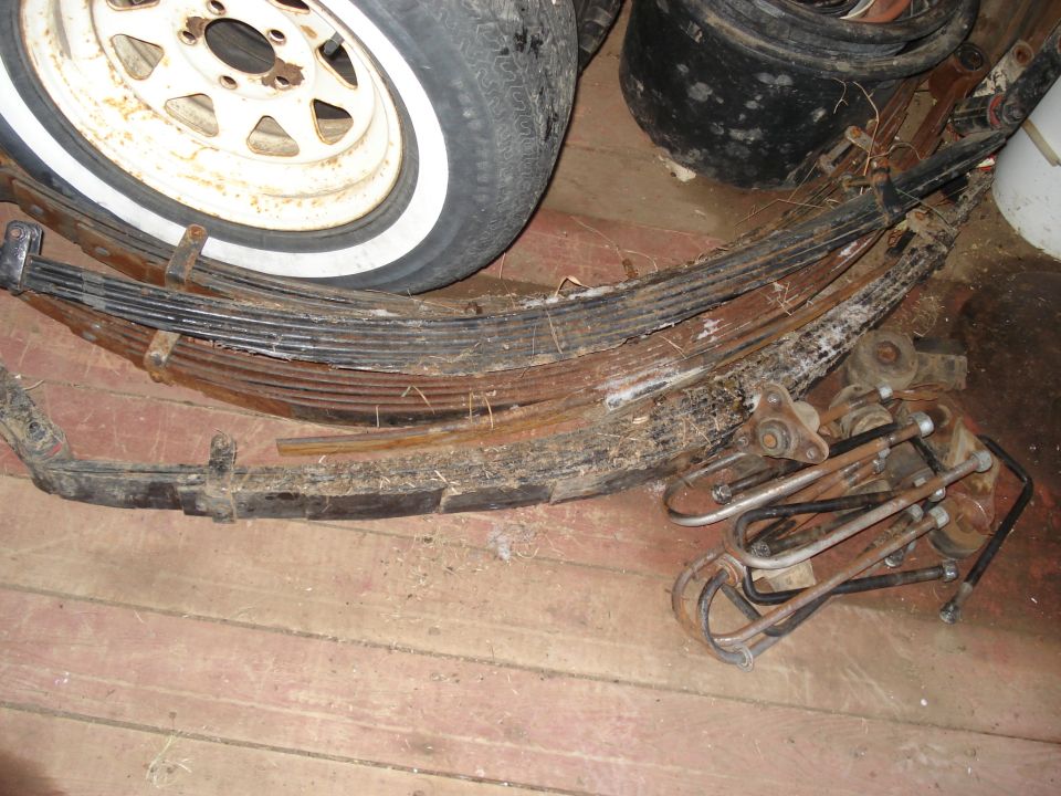 Leaf springs and a tire with a white stripe on a wooden floor