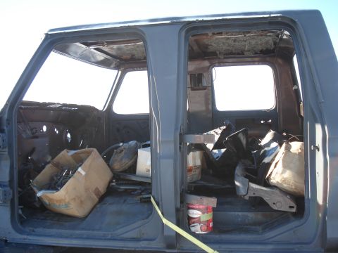1977 Ford F-150 - The interior of a 1977 Ford F-150 cab shows significant damage and is filled with various parts and debris.