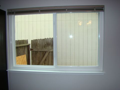 1989 Ford Bronco - View through a window shows a backyard with a wooden fence and vertical siding.