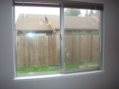 1989 Ford Bronco - A backyard scene is visible through a sliding glass window, showing a wooden fence and residential buildings.