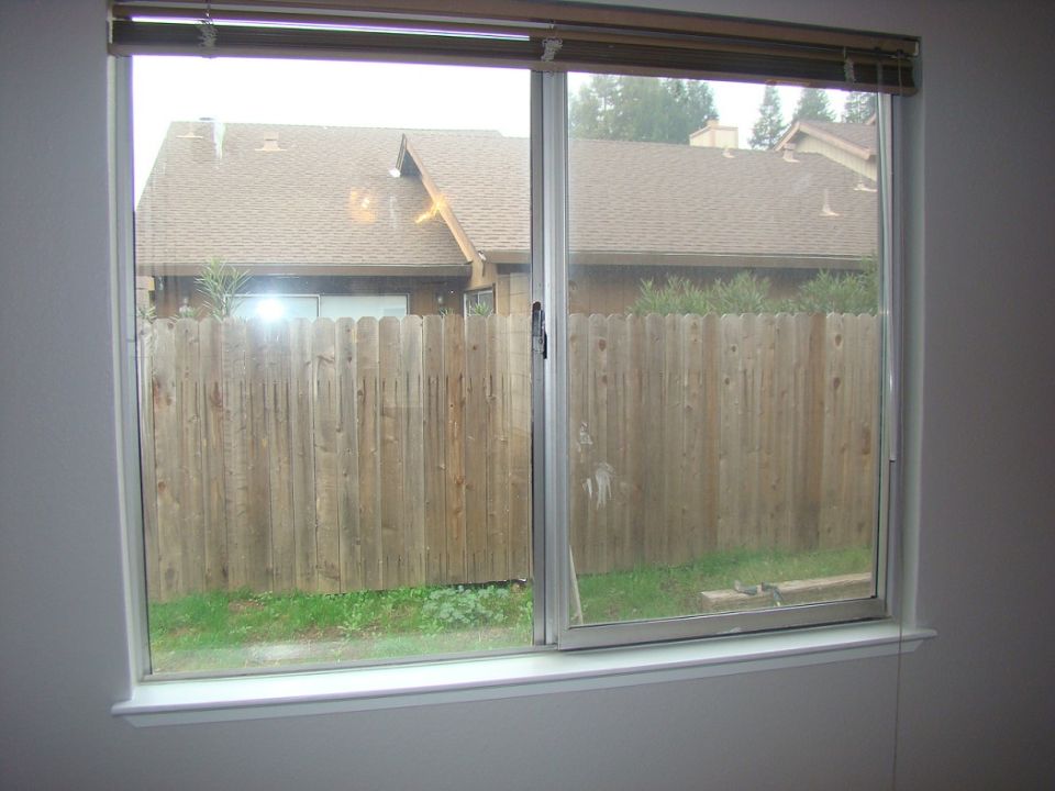 View of a wooden fence and houses through a sliding glass window