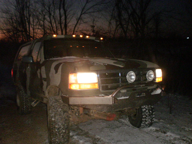 Camouflaged Ford Bronco with aftermarket bumper and roof lights