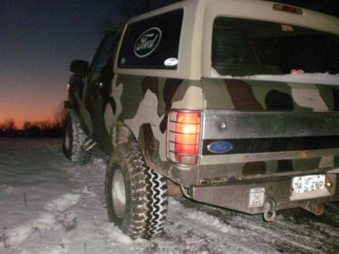 1995 Ford Bronco - Camouflaged 1995 Ford Bronco parked in a snowy field at dusk.