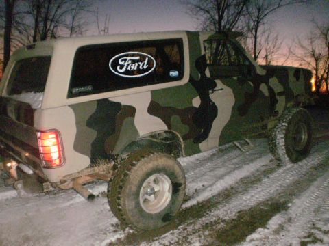 1995 Ford Bronco - This Ford Bronco is covered in camouflage and parked on a snowy, dirt road during twilight.