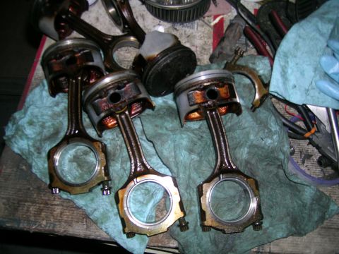 1995 Ford Probe - Engine components, likely pistons and connecting rods, are laid out on a rag, possibly during a rebuild or repair.