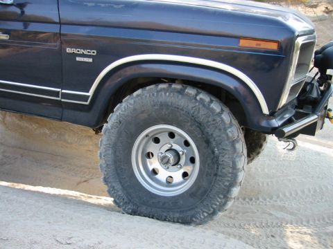 1985 Ford Bronco - This 1985 Ford Bronco features a dark blue paint job with chrome trim and aggressive off-road tires.