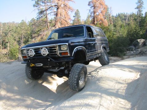 1985 Ford Bronco - This modified Ford Bronco navigates a steep, sandy incline on a wooded trail.