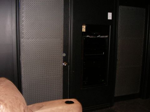 1987 Ford Bronco - A room interior features diamond plate wall panels and a built-in black entertainment unit.