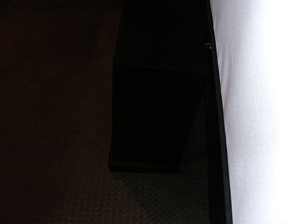 Black box on a diamond plate textured floor next to a white wall