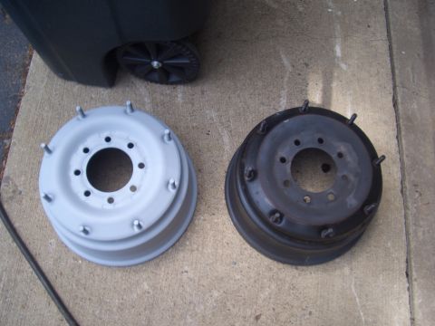 1992 Ford F-150 - A gray-painted brake drum sits next to a black brake drum, with a trash can in the background.