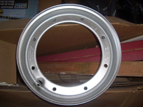1992 Ford F-150 - A single aluminum wheel rim is shown against a background of cardboard boxes and red material.