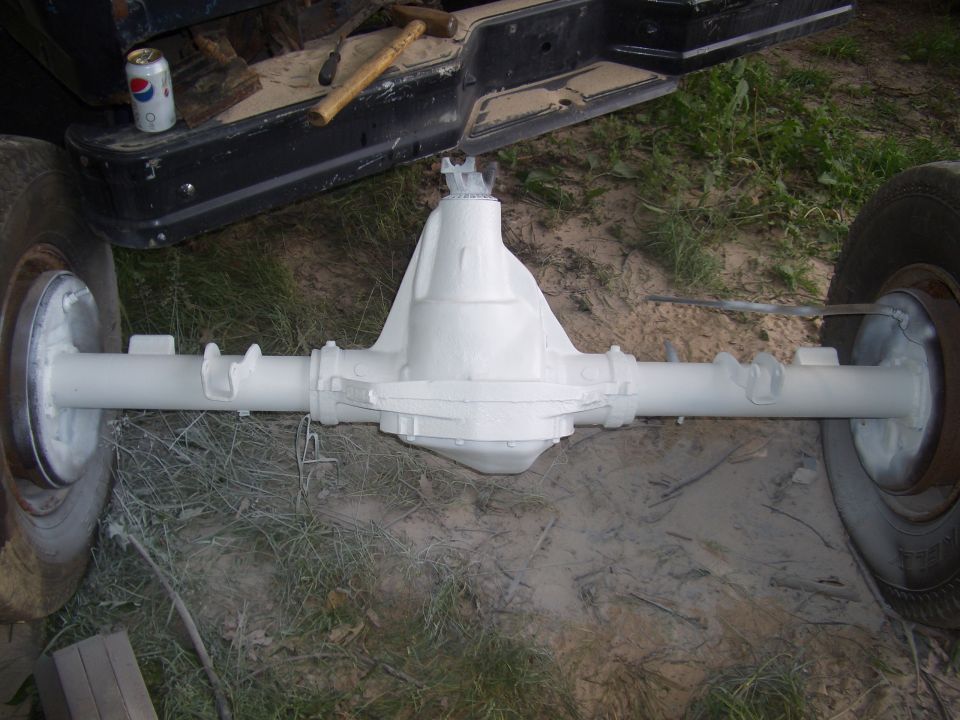 White painted rear axle assembly with brake drums and tires attached