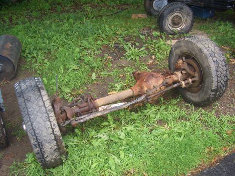 1992 Ford F-150 - Front axle assembly with tires, removed from a vehicle and resting on the grass.