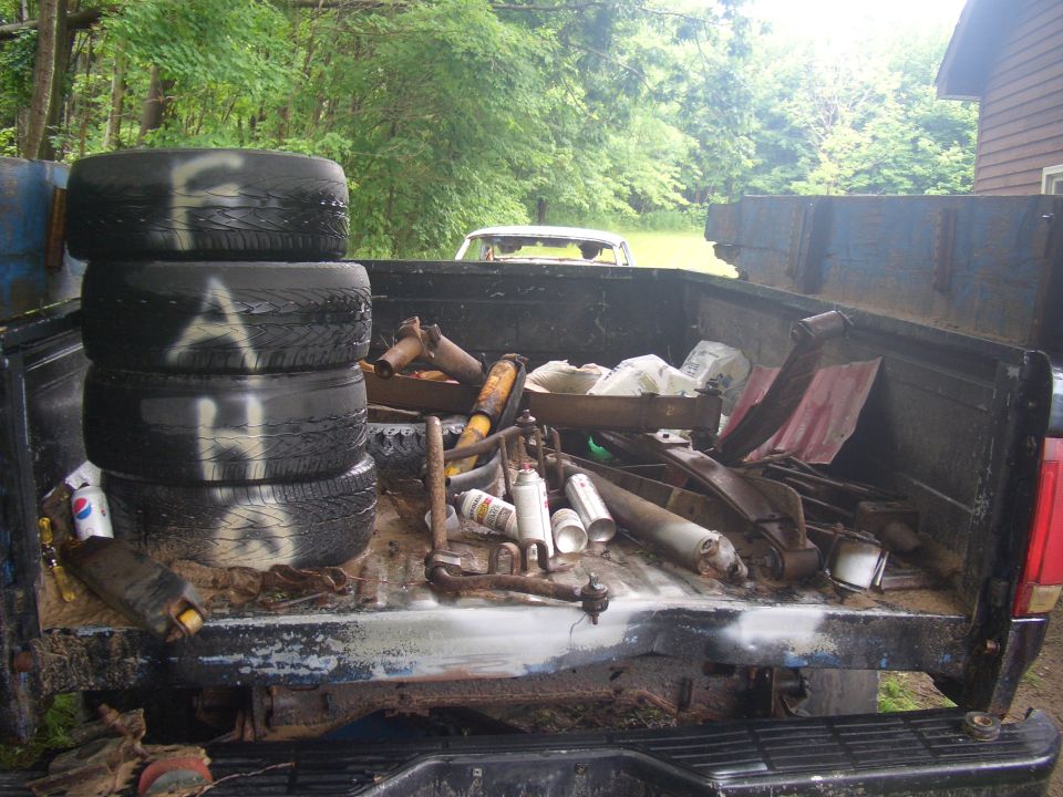 1992 Ford F-150 truck bed filled with tires and car parts; rear view