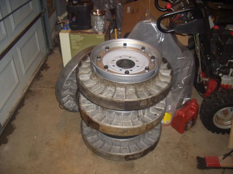 1992 Ford F-150 - Four large truck wheels are stacked, with a fifth wheel placed on top. A red oil container is visible to the right.
