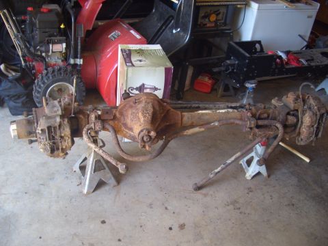 1992 Ford F-150 - A heavily rusted rear axle assembly is supported by jack stands in a garage setting.