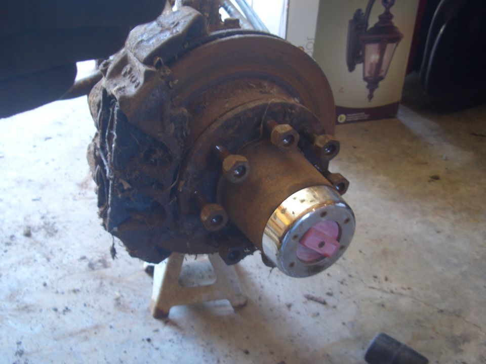 Truck front wheel hub and brake assembly on jack stands, covered in dirt and rust