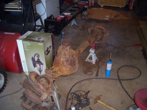1992 Ford F-150 - Rusty truck axle assembly on jack stands in a garage setting with various tools.