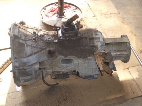 1992 Ford F-150 - A dirty transmission is shown removed from a vehicle, resting on a floor.