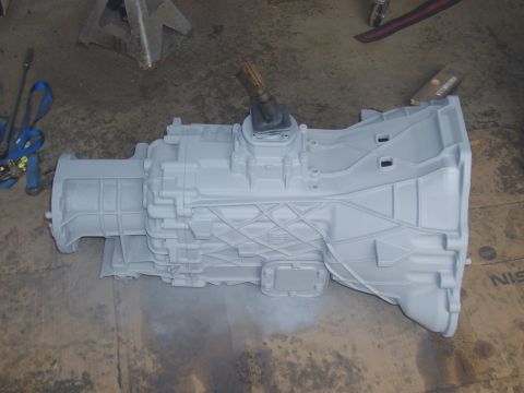 1992 Ford F-150 - Transmission assembly painted gray, resting on a concrete floor with shop equipment in the background.