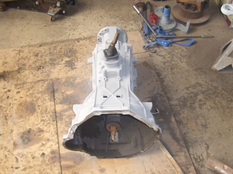 1992 Ford F-150 - A manual transmission sits on a floor, possibly in a garage or workshop, with tools and other parts in the background.