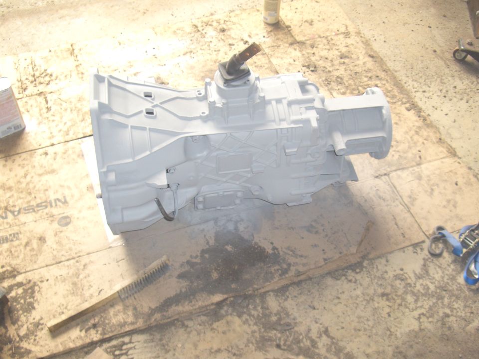 Gray painted transmission with a black shifter on a wooden surface with a brush