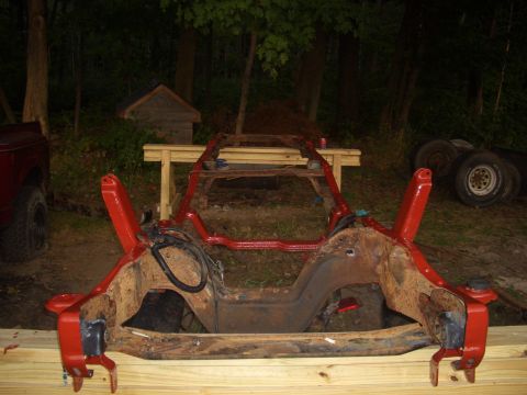 1992 Ford F-150 - Truck frame undergoing restoration work, painted red and supported by wood.