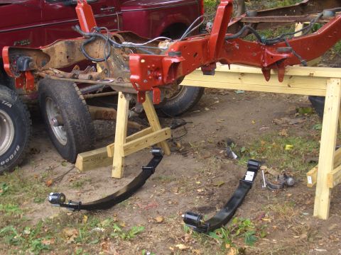 1992 Ford F-150 - The frame of a red truck is supported by sawhorses, with leaf springs laid out nearby.