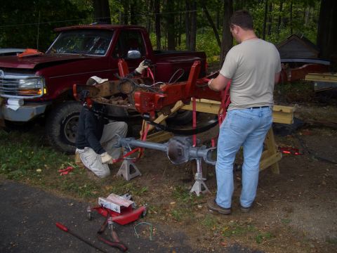 1992 Ford F-150 - Two people are working on the chassis and axle of a 1992 Ford F-150 truck.