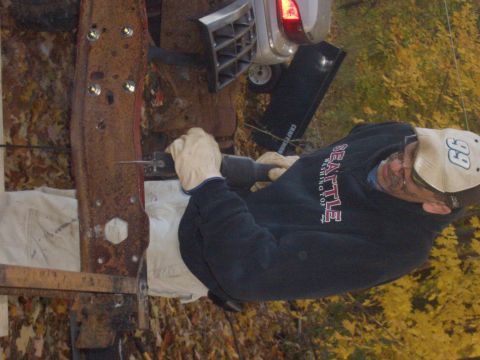 1992 Ford F-150 - Man working on a rusty metal frame with a reciprocating saw.