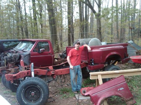 1992 Ford F-150 - A man poses next to a disassembled red pickup truck, with the engine and some body panels removed.