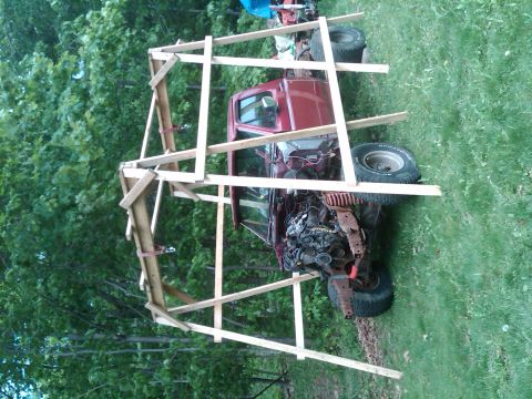 1992 Ford F-150 - A red 1992 Ford F-150 pickup truck is shown in a state of construction, partially covered by a wooden frame.