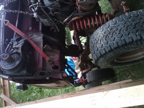 1992 Ford F-150 - The engine bay and suspension of a 1992 Ford F-150 are visible, red coil springs and a large off-road tire.