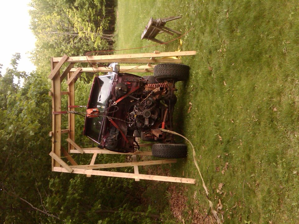 Truck chassis and cab supported in a wooden frame jig in a grassy yard