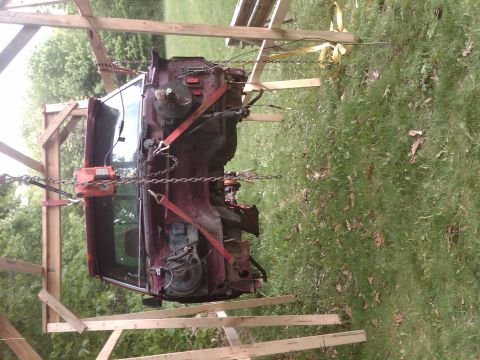1992 Ford F-150 - The body of a truck is suspended in the air by a wooden frame and chains, likely for repairs or modification.